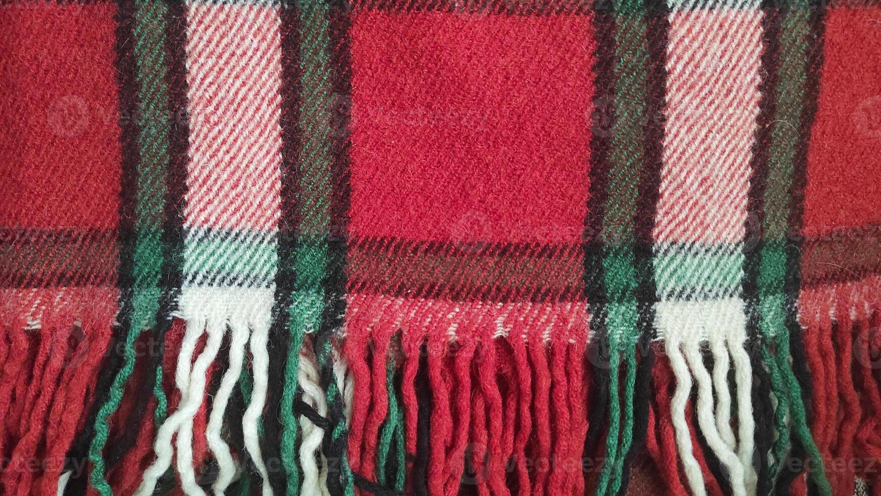 close-up of a classic red and green checkered wool blanket with fringed edges, textile patterns or cozy winter background. Ideal for backgrounds, clothing mockups or seasonal decor concepts. photo