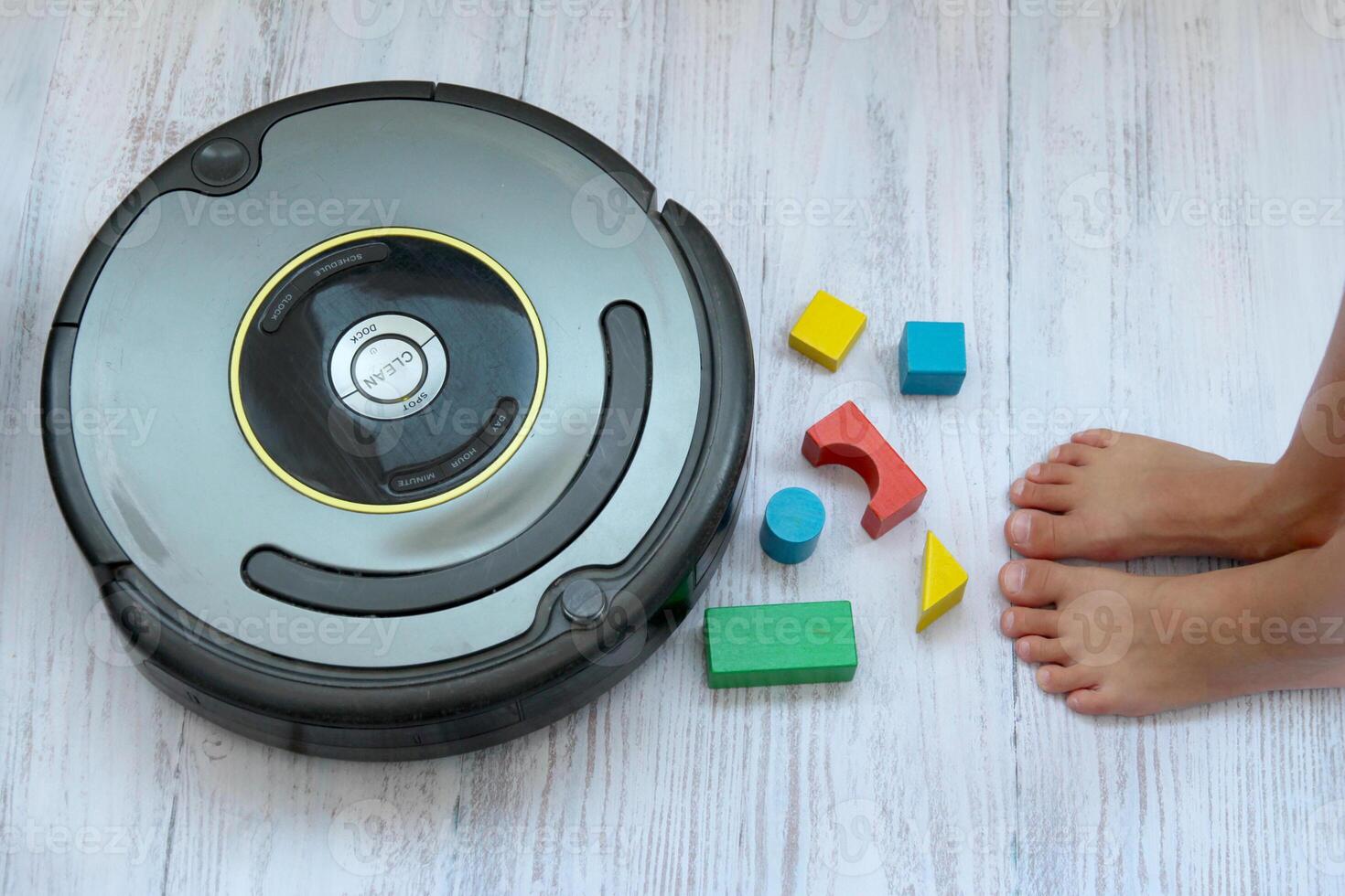 A robot vacuum glides across the light parquet floor, efficiently cleaning and vacuuming. The photo showcases the use of modern technology in a playful, family-oriented setting