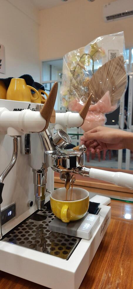 Close up Barista making coffee for customer in cafe. Woman working in coffee shop wearing an apron. Makassar, South Sulawesi, Indonesia - August 11 2024 photo