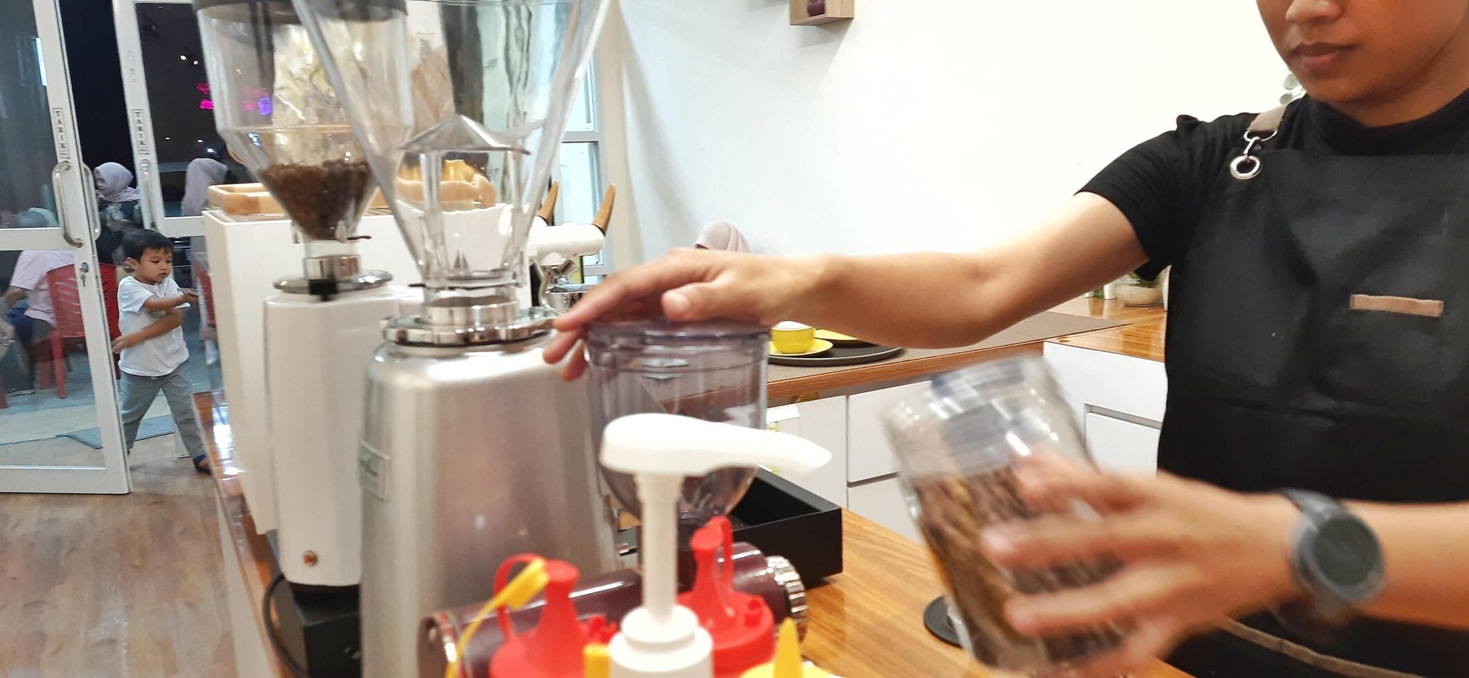 Close up Barista making coffee for customer in cafe. Woman working in coffee shop wearing an apron. Makassar, South Sulawesi, Indonesia - August 11 2024 photo