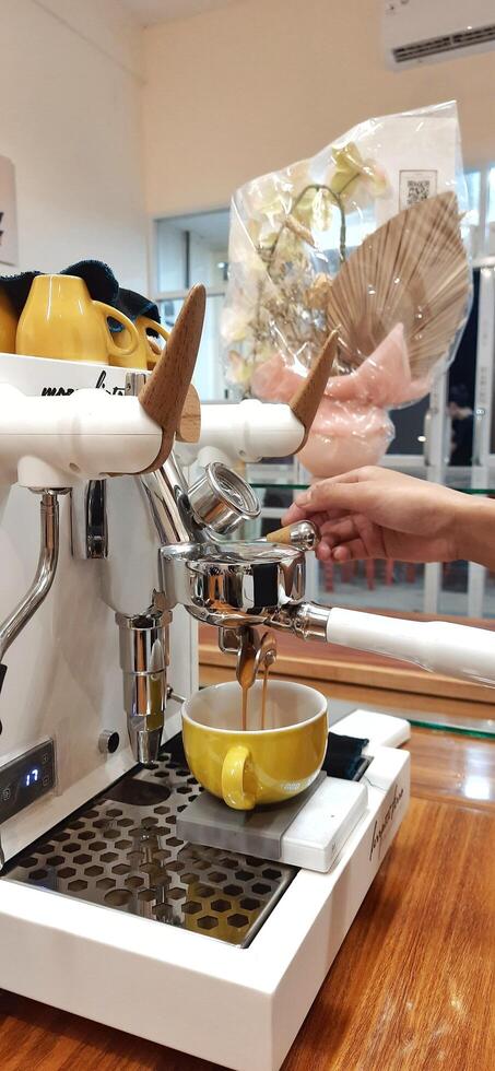 Close up Barista making coffee for customer in cafe. Woman working in coffee shop wearing an apron. Makassar, South Sulawesi, Indonesia - August 11 2024 photo