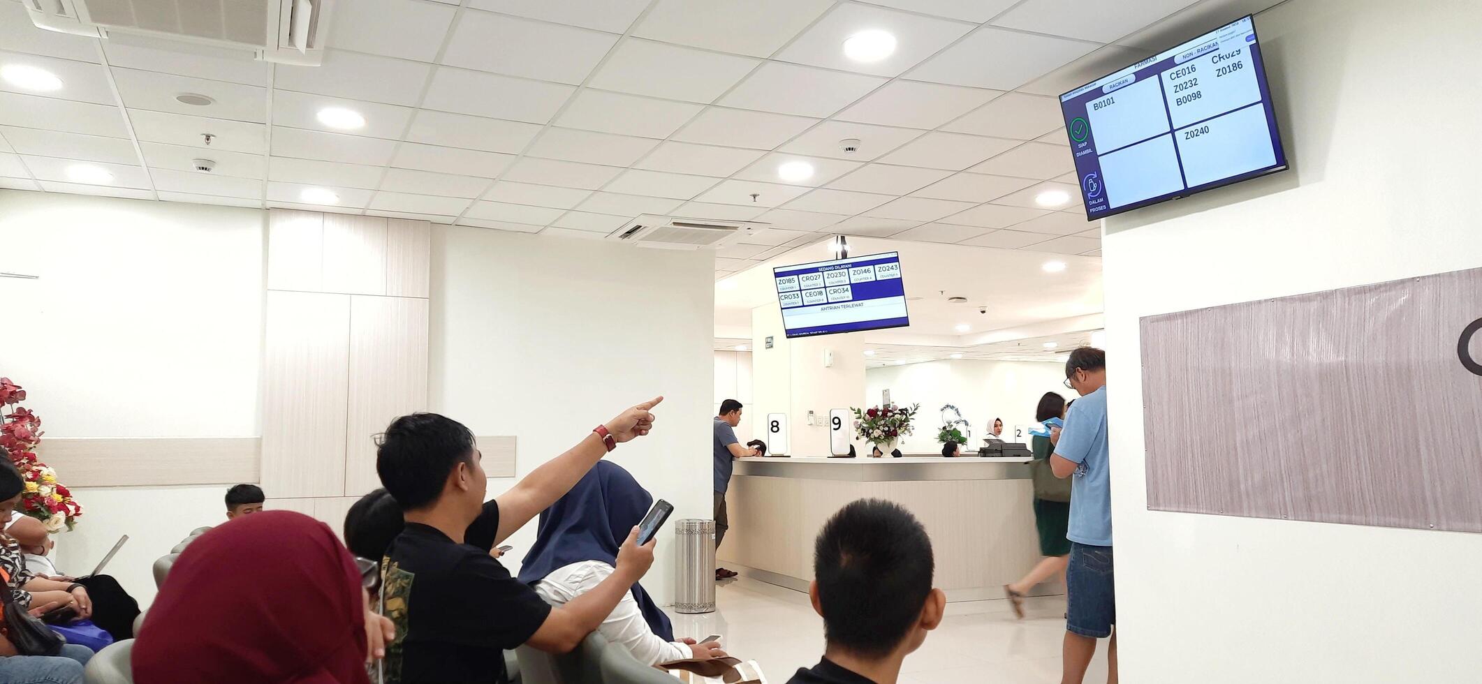 Atmosphere of patient queues to receive medical services at waiting area hospital. Makassar, South Sulawesi, Indonesia - August 12 2024 photo