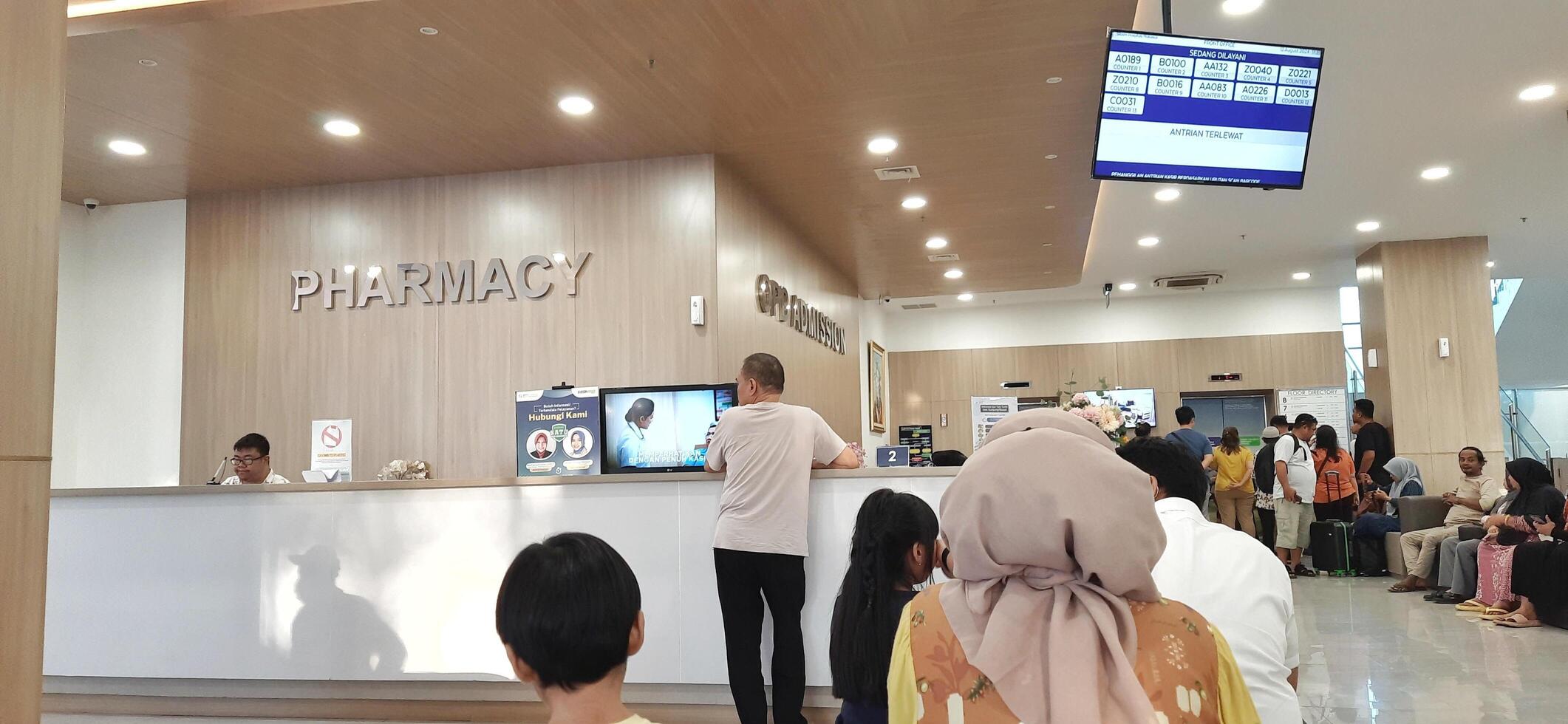 Atmosphere of patient queues to receive medical services at waiting area hospital. Makassar, South Sulawesi, Indonesia - August 12 2024 photo