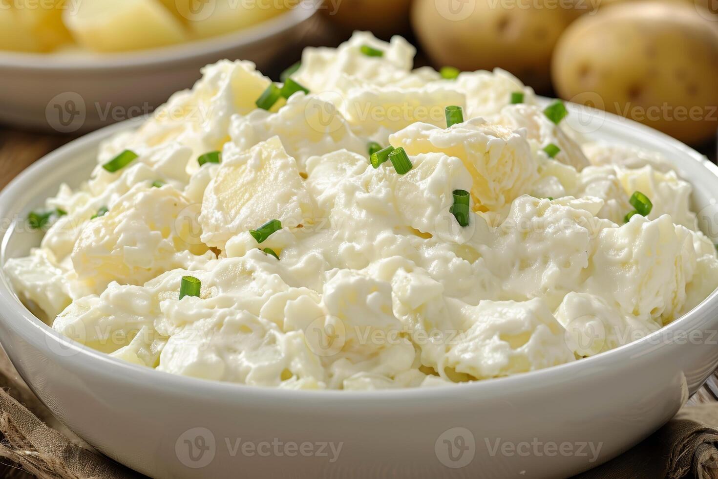 Creamy potato salad garnished with chives in a white bowl. Classic side dish for summer photo