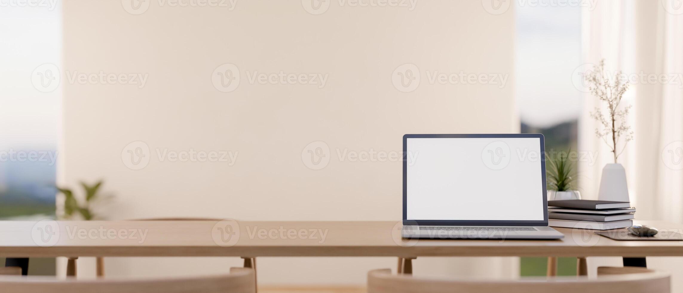 A wooden table featuring a laptop with a white screen mockup and decor, set in a bright room. photo