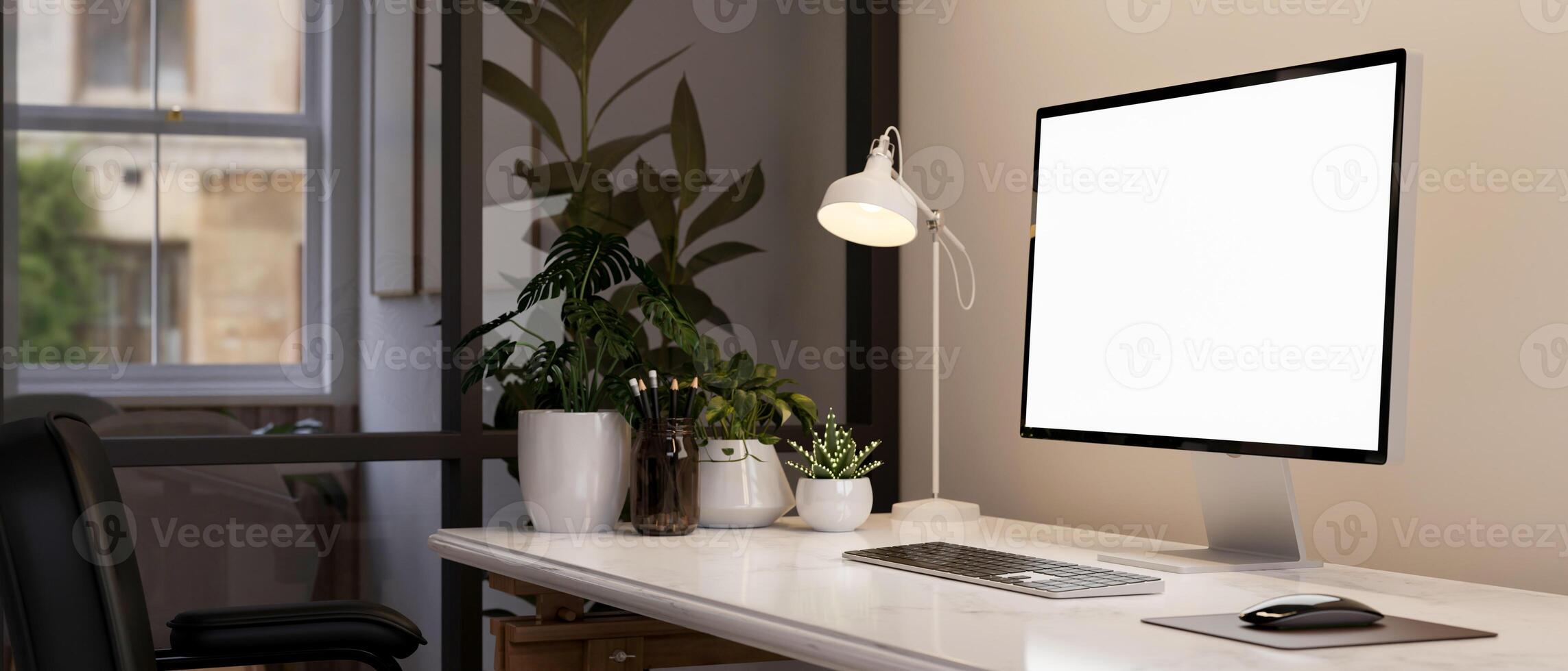 A computer mockup, a table lamp, and decorative plants on a table in a modern office room. photo