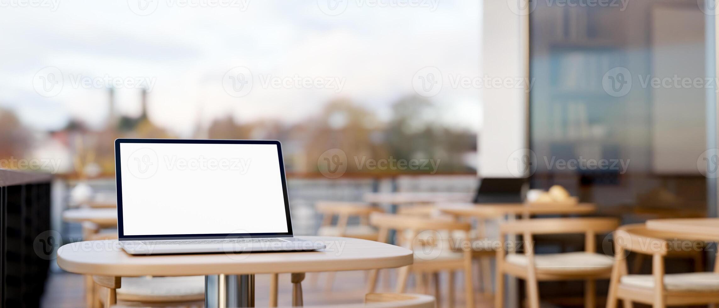 A laptop computer mockup on a table on an outdoor terrace of a coffee shop on a daytime. photo