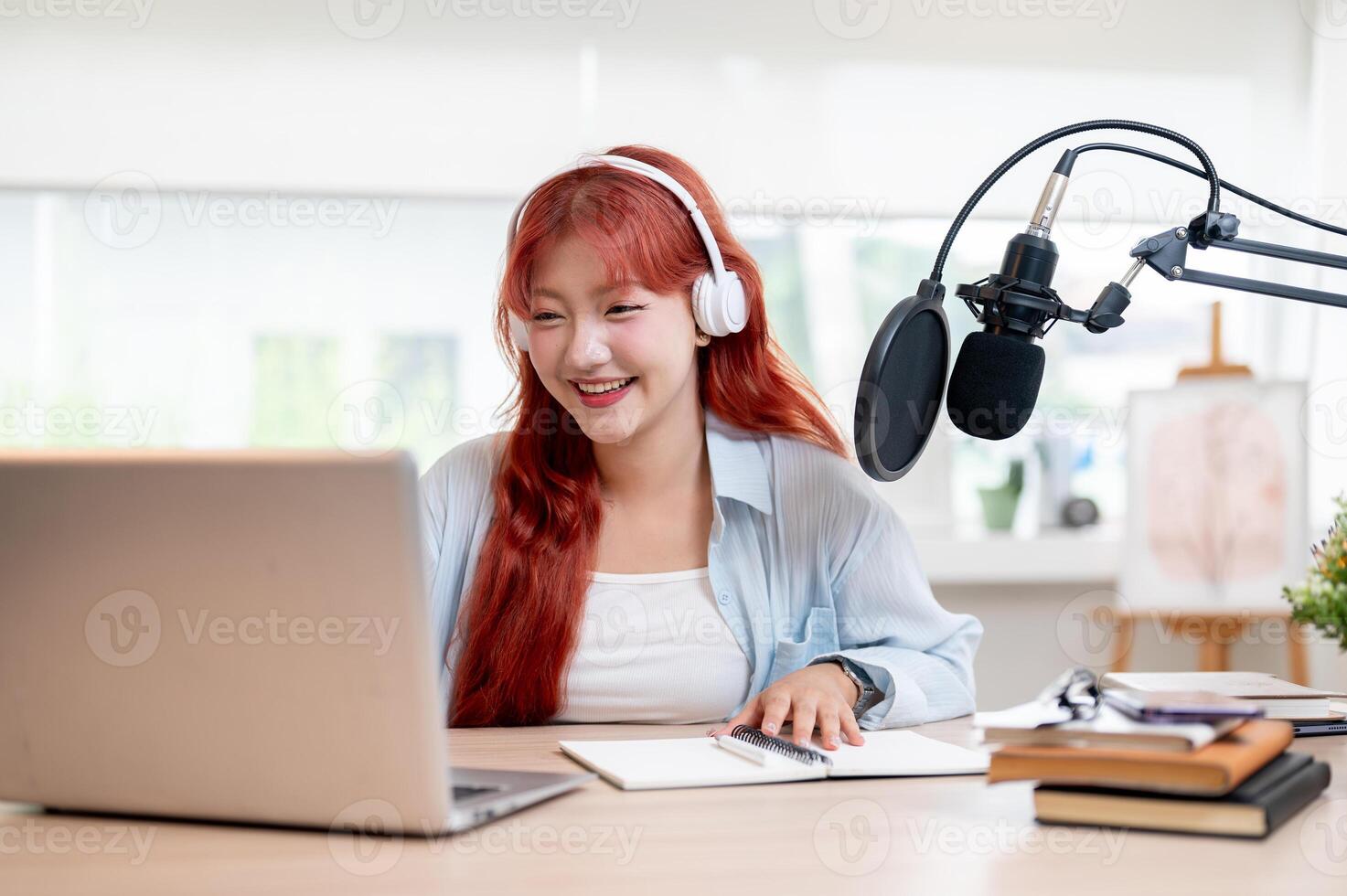 A happy Asian female podcaster is reading live comments on her online channel while broadcasting. photo