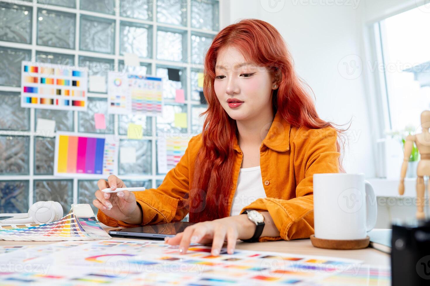 Beautiful Asian female designer is working in her studio, using a digital tablet and color swatches. photo