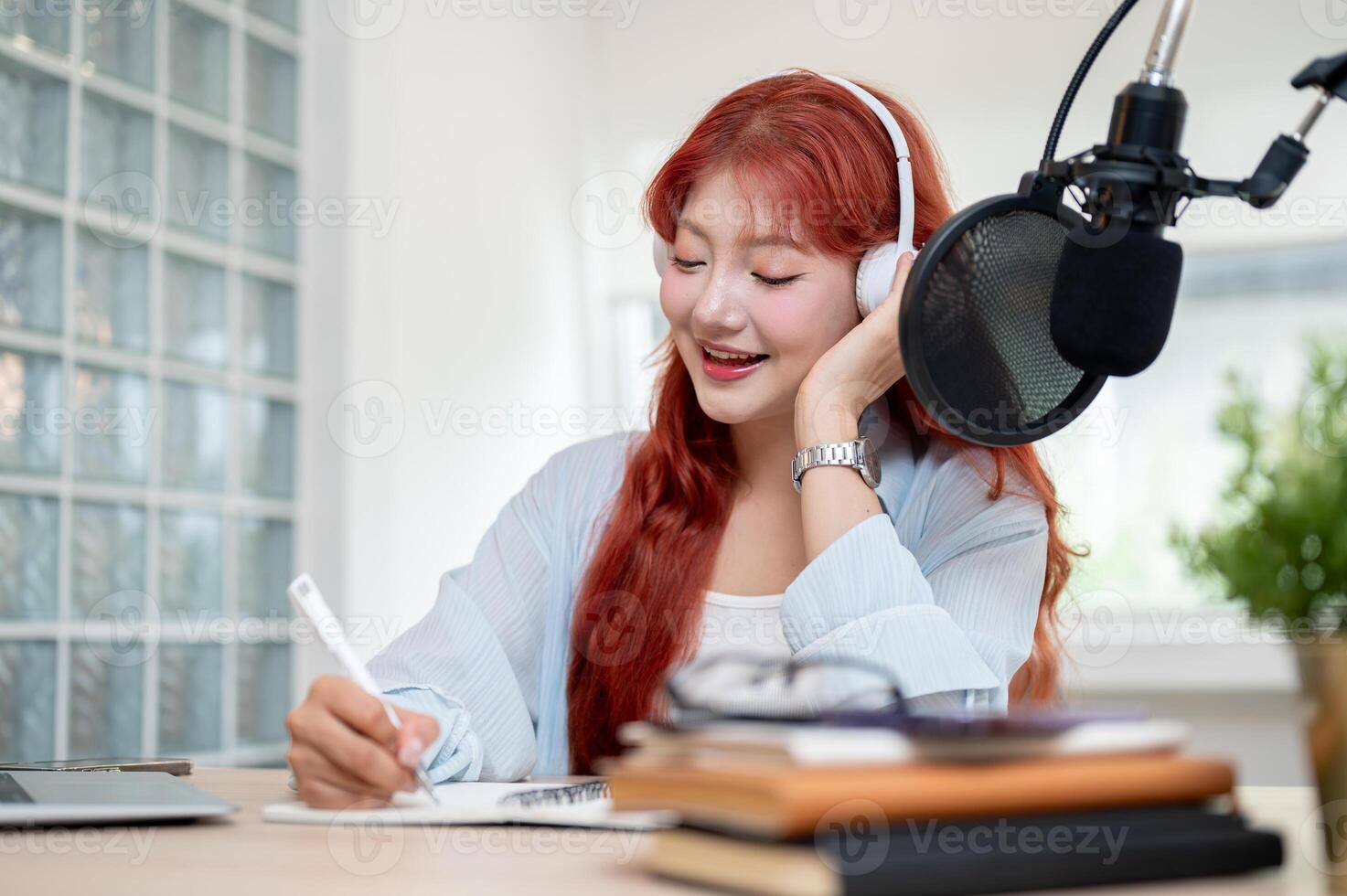 A beautiful Asian female podcaster is reading from the script while recording her podcast. photo