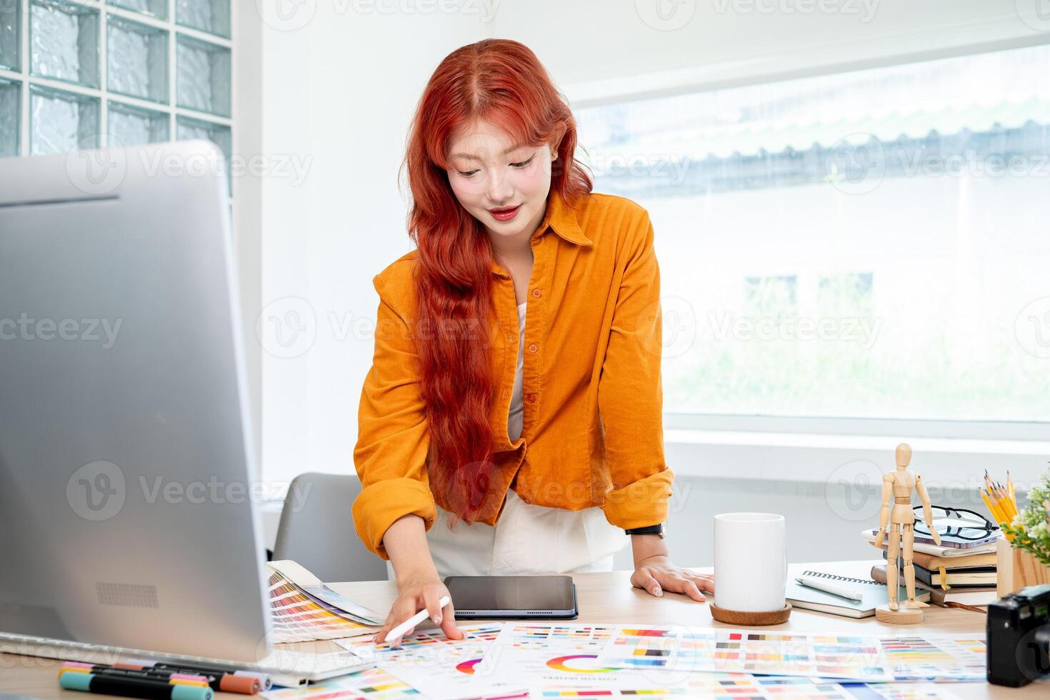 A beautiful Asian female graphic designer is selecting colors from a set of color swatches. photo