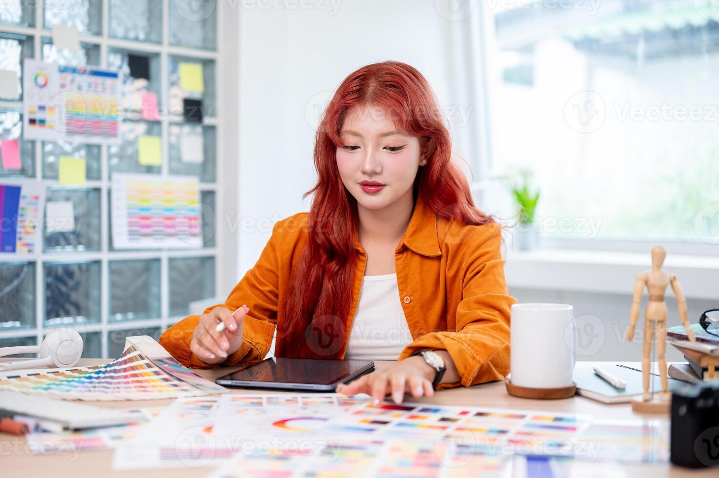 A beautiful and creative Asian female graphic designer is working at her desk in the studio. photo