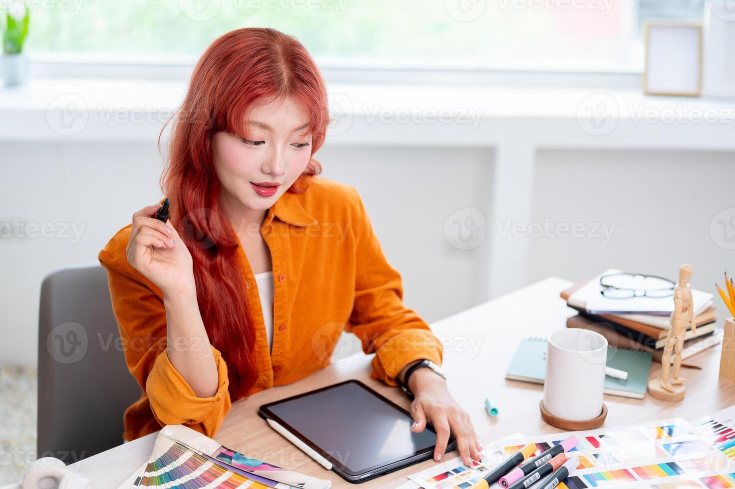 A creative, focused Asian female graphic designer is working at her desk in the studio. photo