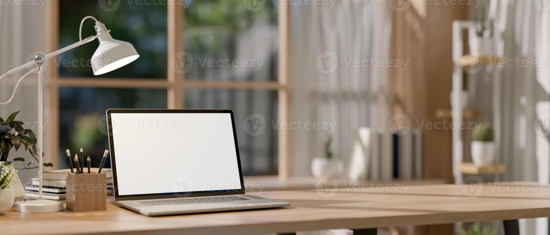 A laptop with a blank screen mockup and stationery on a wooden table in a bright minimalist room. photo