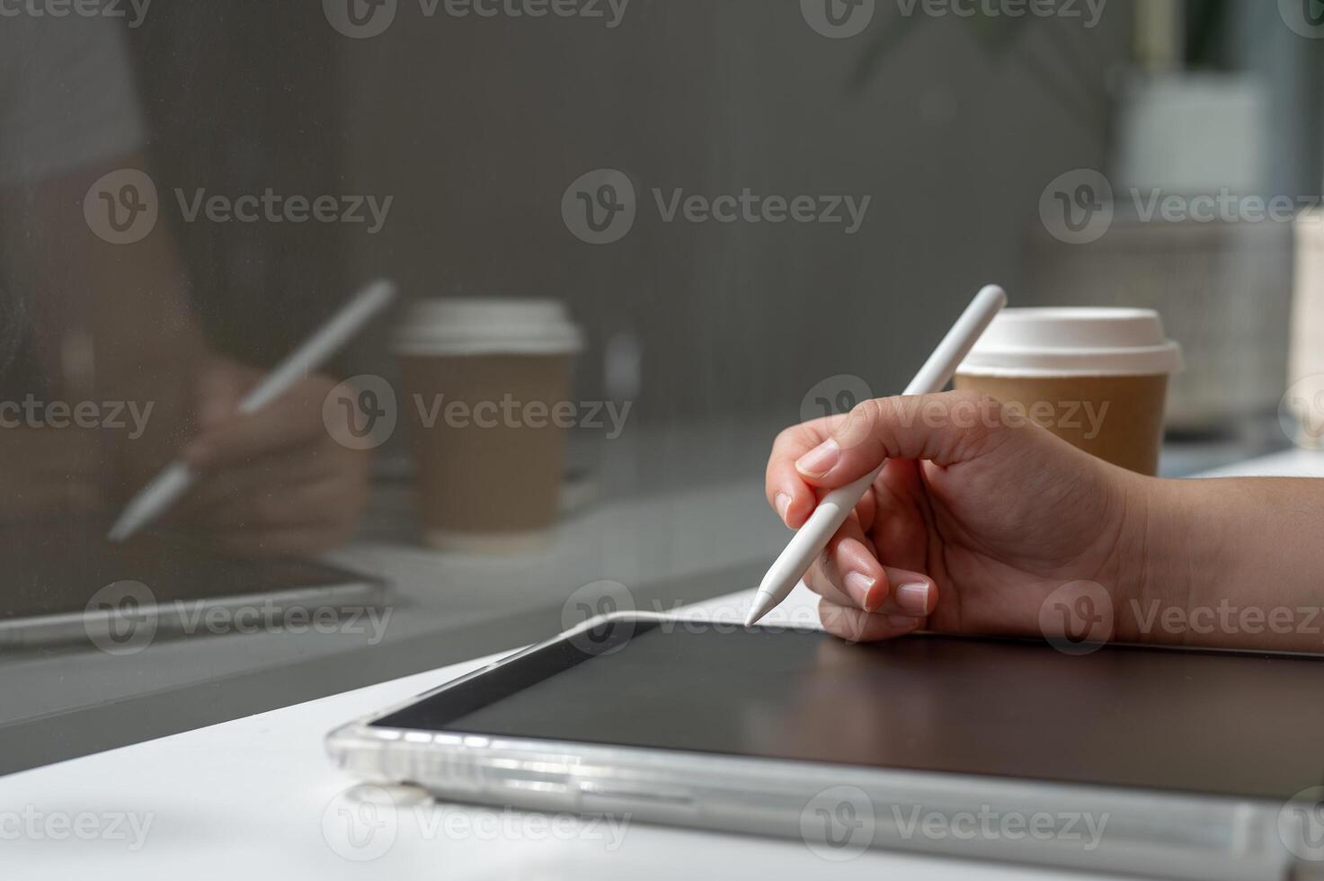 A woman holding a stylus pen, writing on a digital tablet, working remotely from a coffee shop. photo