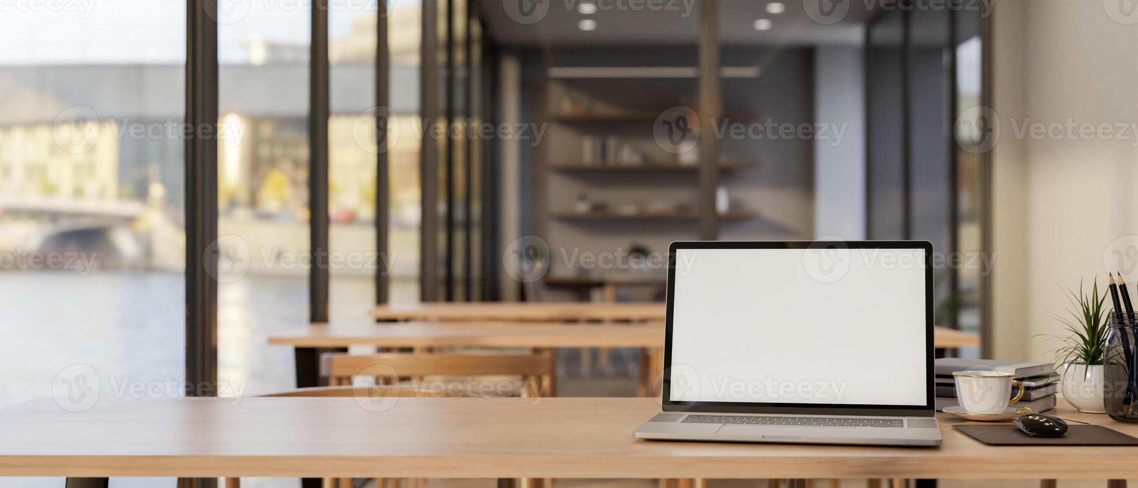A laptop mockup on a wooden table in a cafe seating area or in a co-working space in an office. photo