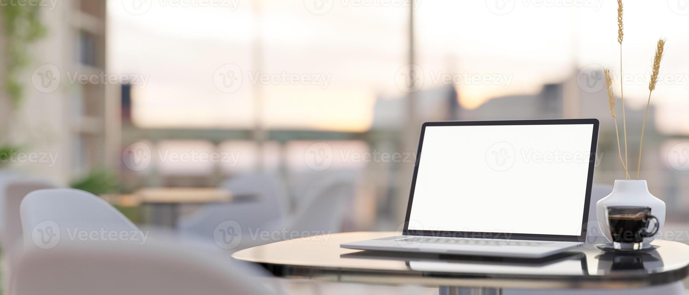 A laptop computer with a white-screen mockup on a table in a modern cafe sitting area. photo