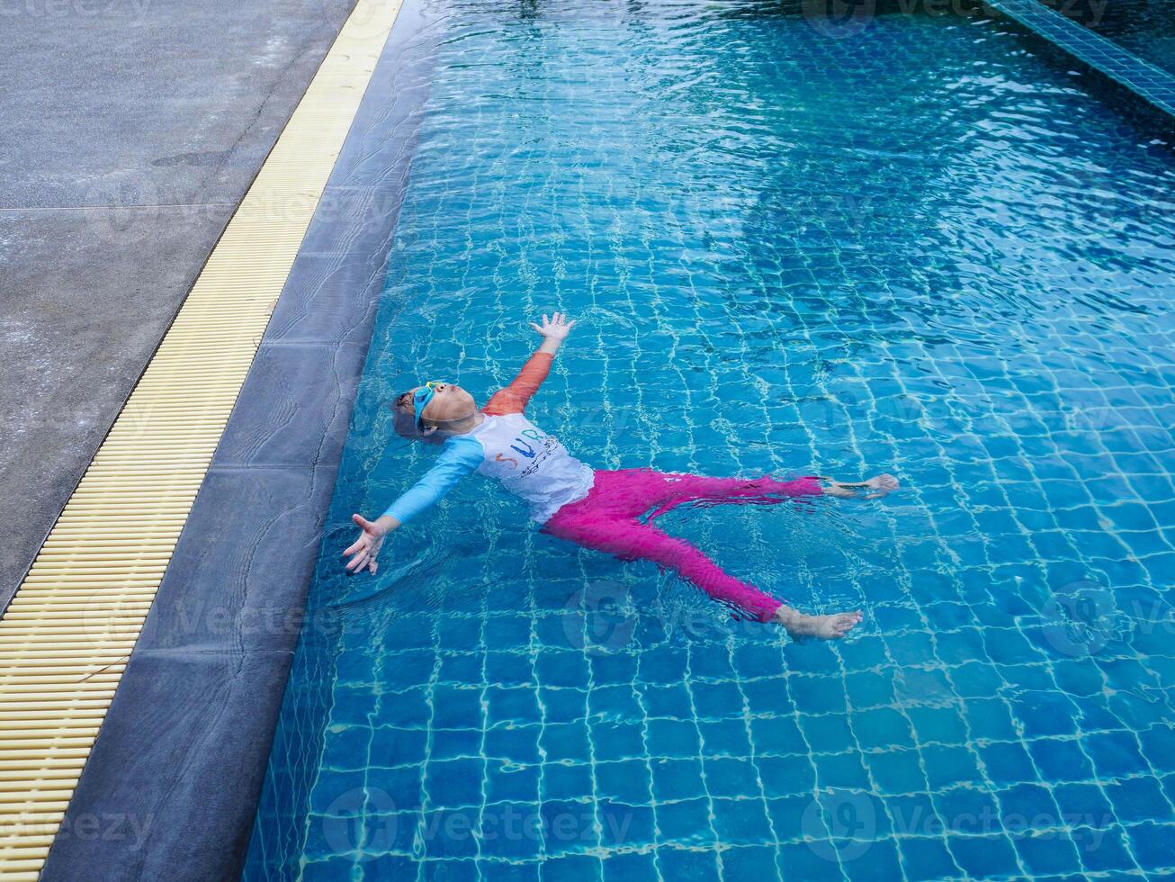 A little girl enjoys playing in the outdoor swimming pool. photo