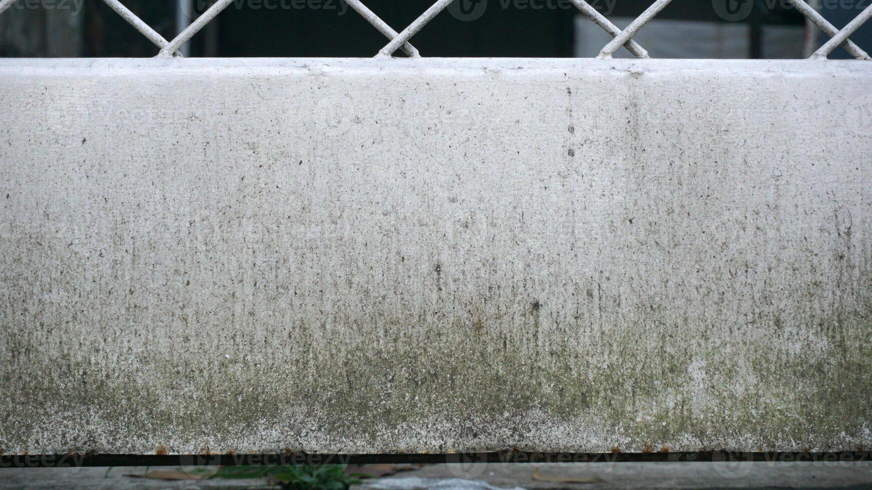 White concrete wall with grille and green grass. Dirty background texture. photo