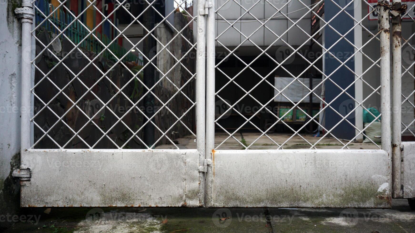 Old white metal gate on the side of the road. Mossy and grunge texture. photo