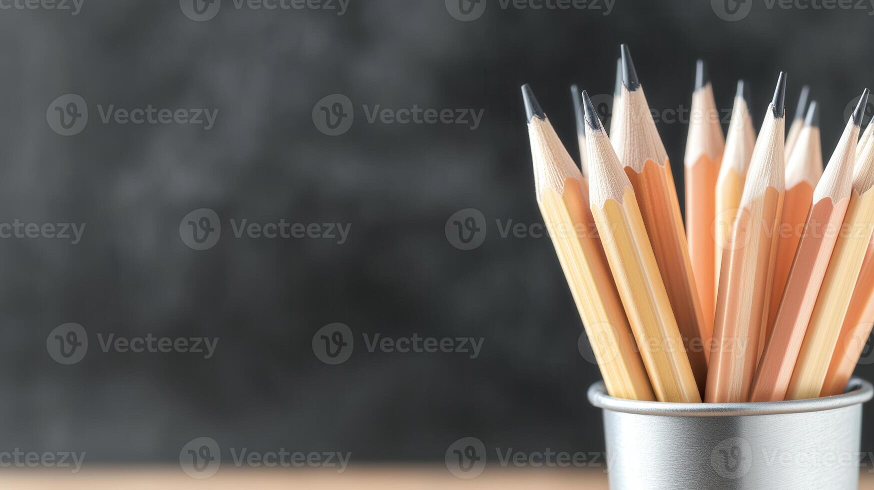 A collection of sharpened pencils arranged in a metallic cup on a neutral background, ideal for educational and creative projects. photo