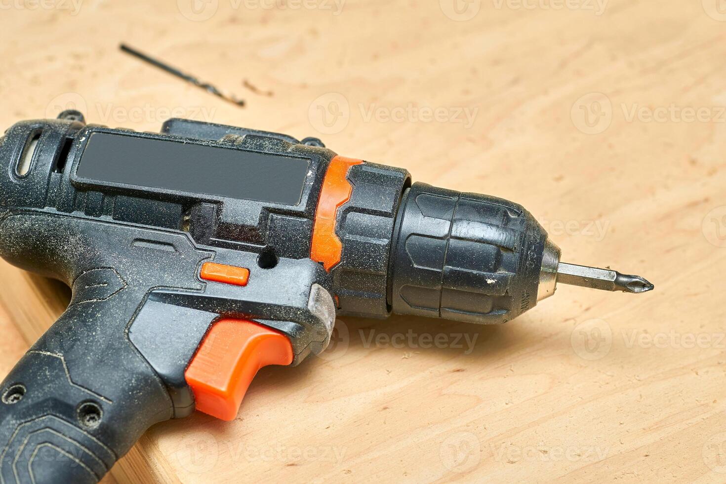 Electric drill,screwdriver on a plywood wooden surface with sawdust in workshop photo