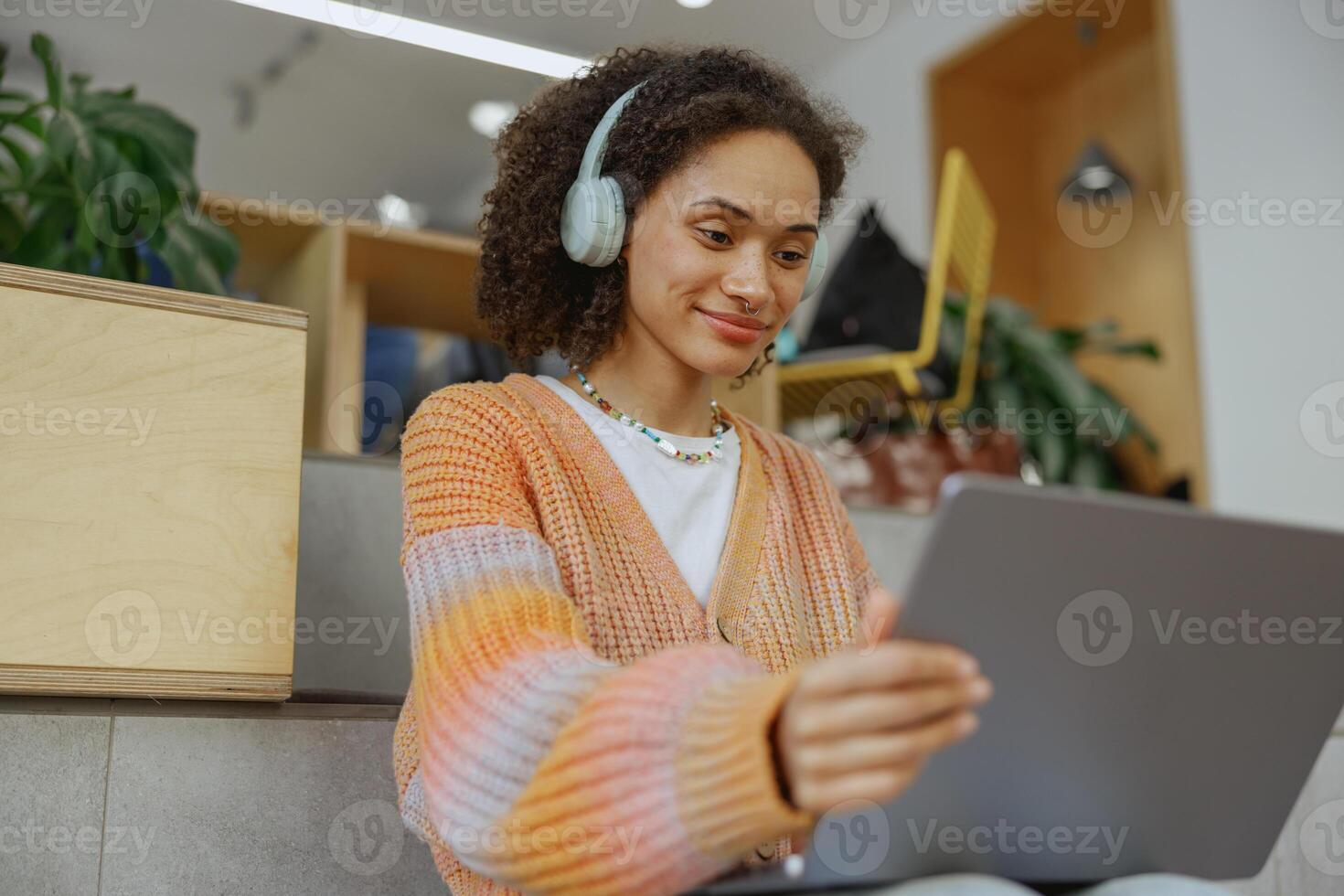 A happy woman with headphones smiles while using a tablet computer photo