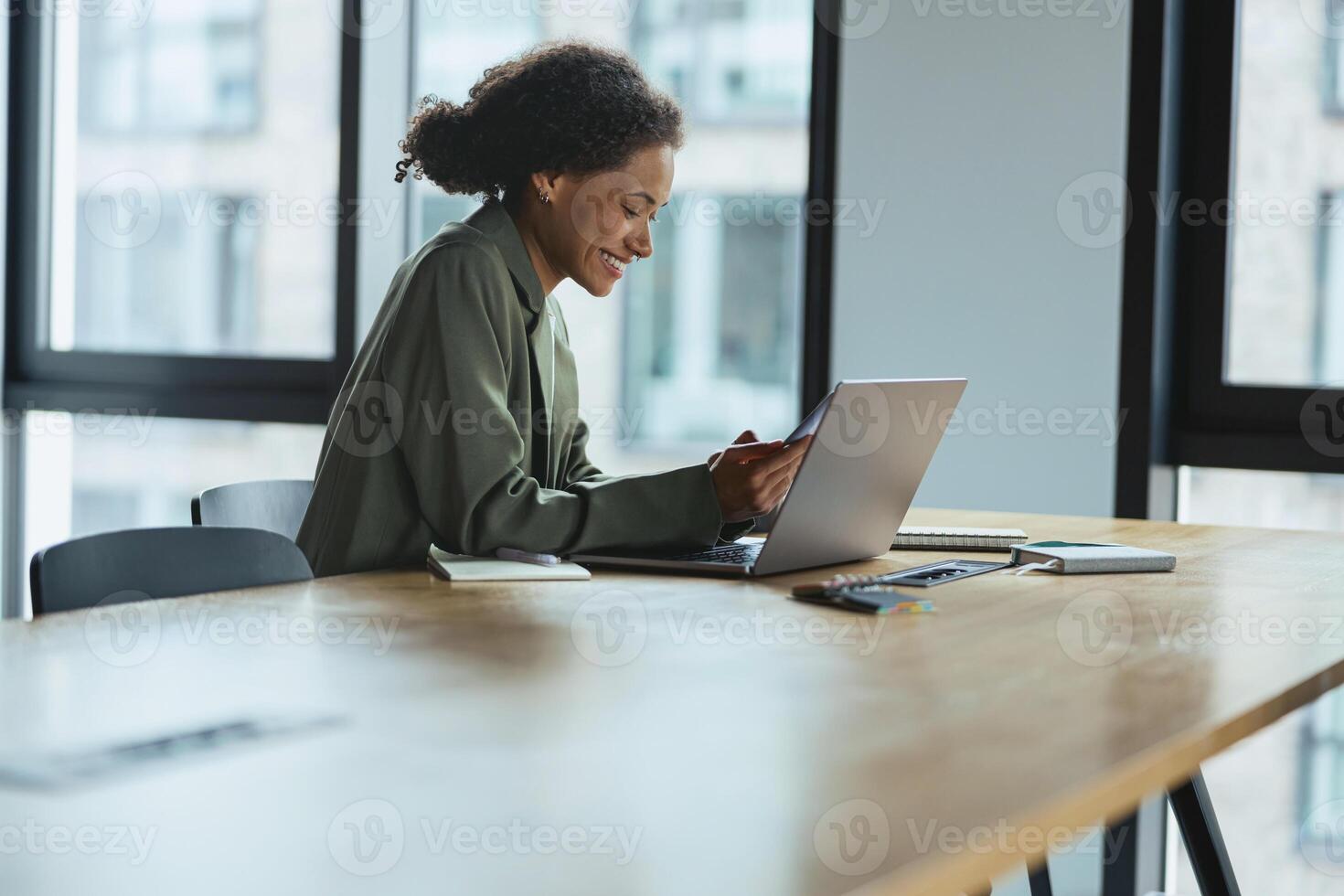 A woman sits at a table using a laptop computer in a building interior photo