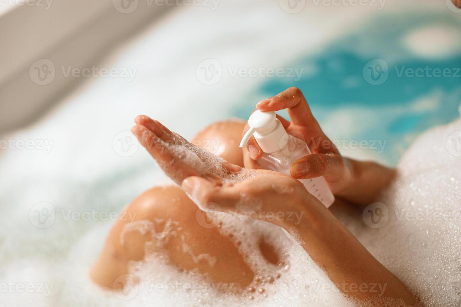 A woman is bathing, applying soap to her hands as a gesture of selfcare photo