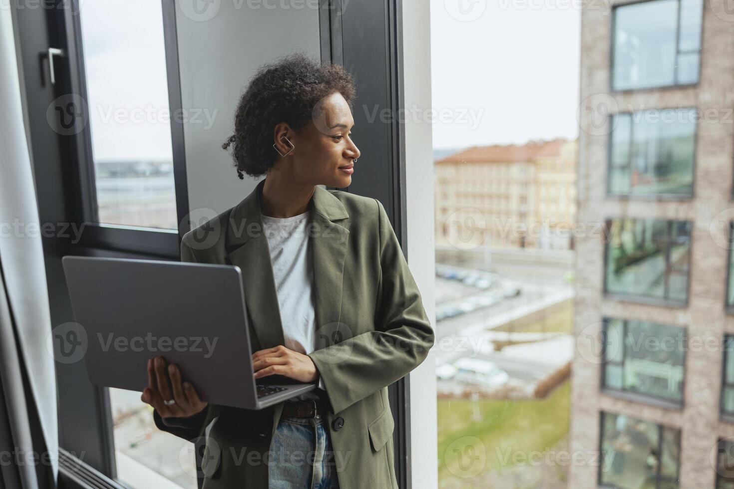 a woman is using a laptop computer while looking out of a window photo