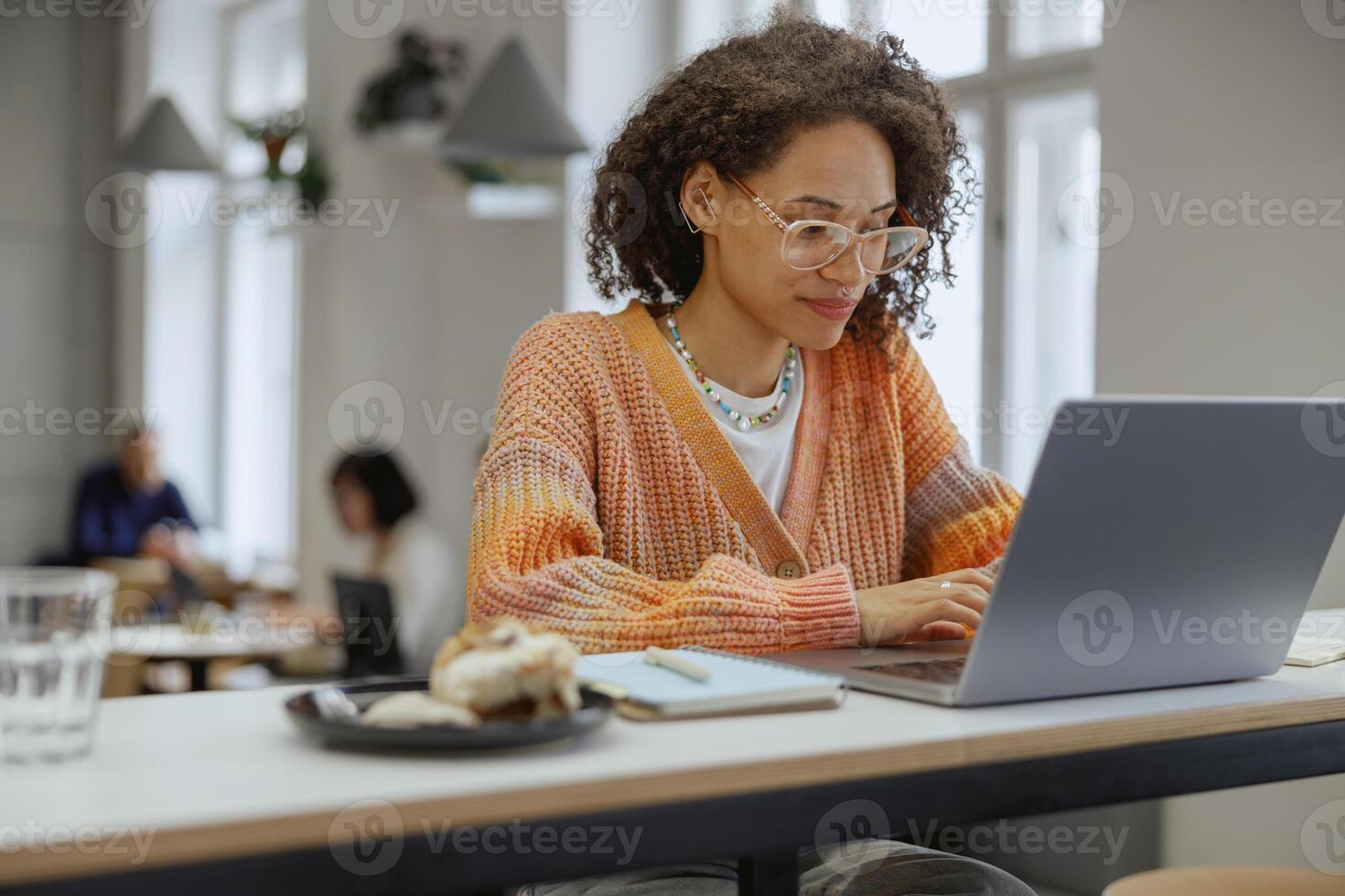 A woman is seated at a desk utilizing a laptop computer in a modern cafe photo