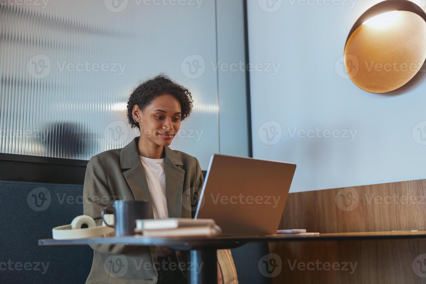 TV presenter using laptop at table in building event, with fun display device photo
