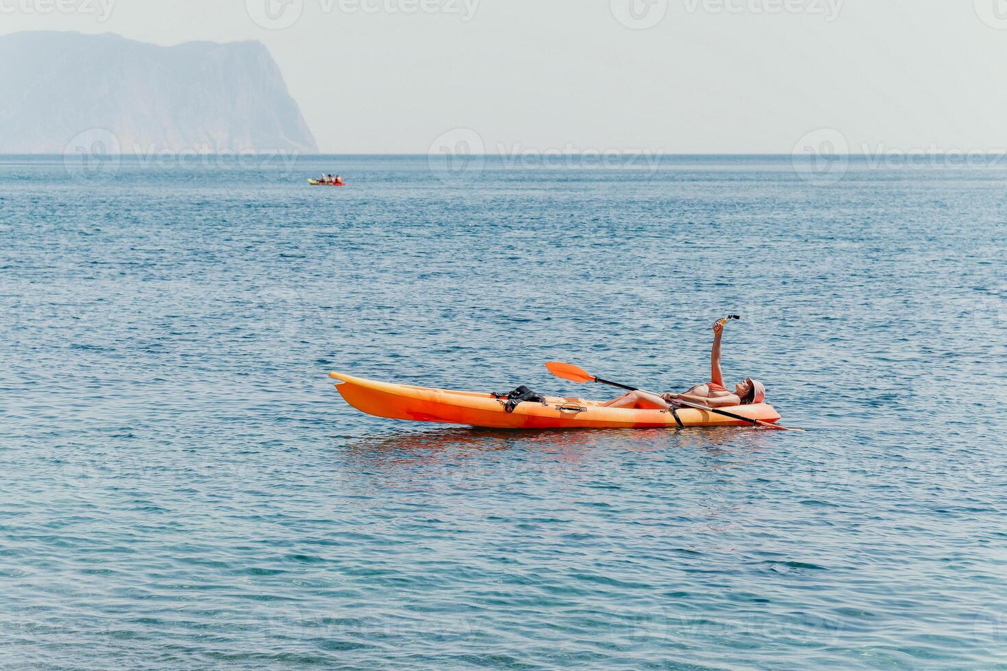 Woman sea kayak. Happy smiling woman paddling in kayak on ocean. Calm sea water and horizon in background. Active lifestyle at sea. Summer vacation. photo