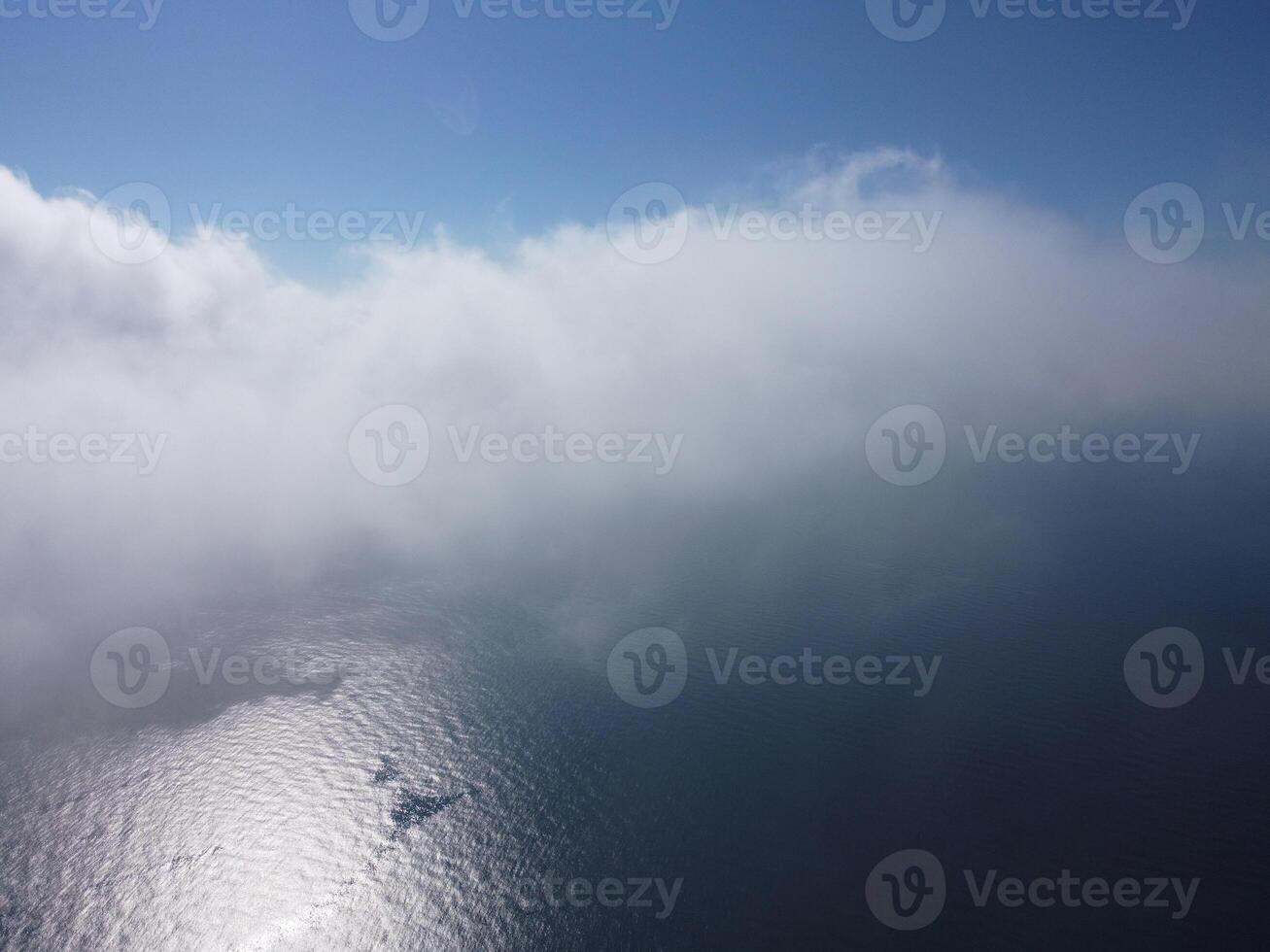 Aerial view. The drone flies over foggy and fluffy clouds. Blue sky sun and sea fog. Abstract aerial nature summer ocean sunset sea and sky background. Vacation, travel and holiday concept photo