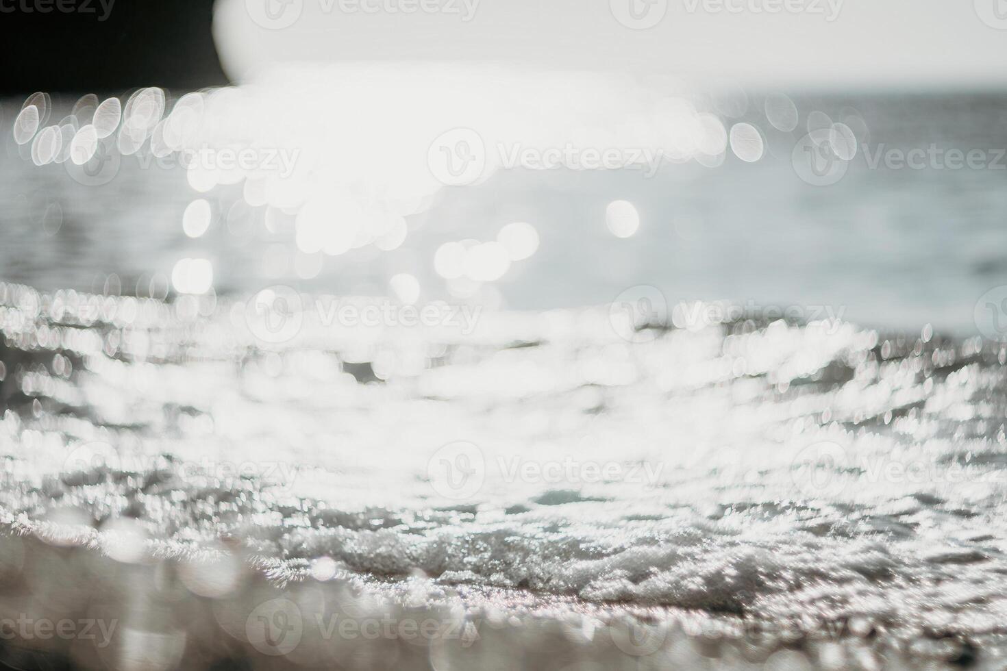 Blurred golden sea at sunset. The sun reflects and sparkles on the waves with bokeh, illuminating the golden sea. Holiday recreation concept. Abstract nautical summer ocean sunset nature background. photo