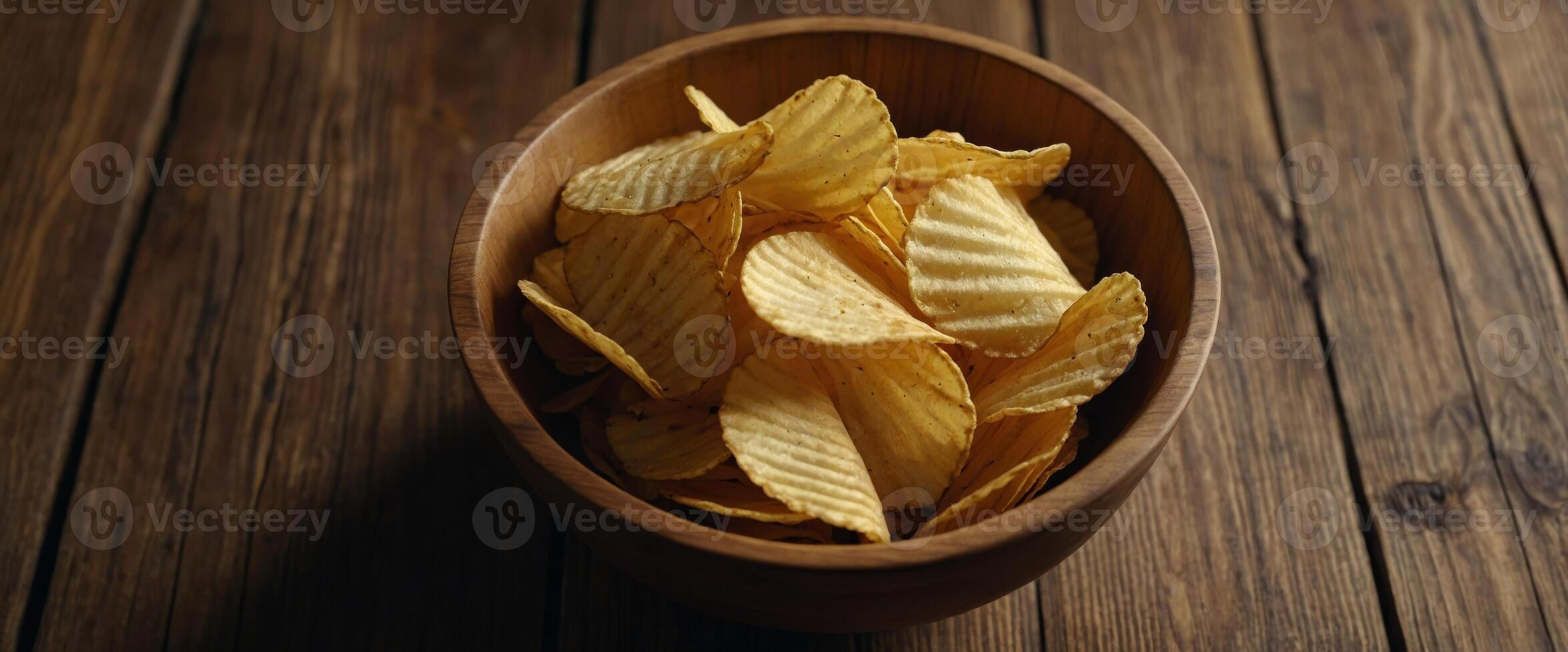 Corrugated golden potato chips in a wooden bowl on rustic wooden table Top view with Empty space for text , soft light, close up, macro. photo