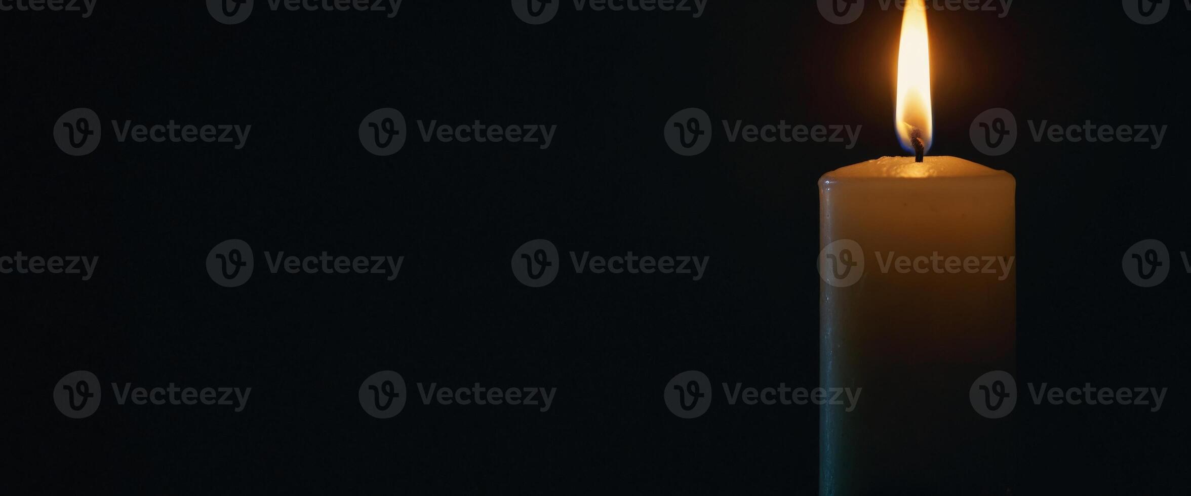 In the darkness, the glow of a solitary candle illuminates the surroundings. photo