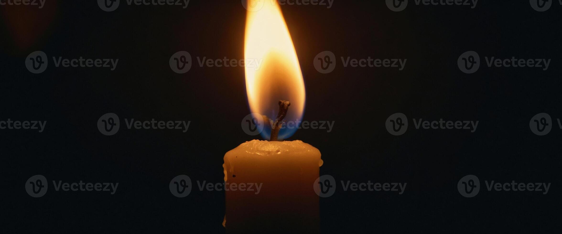 The solitary flame of a candle pierces the darkness. photo
