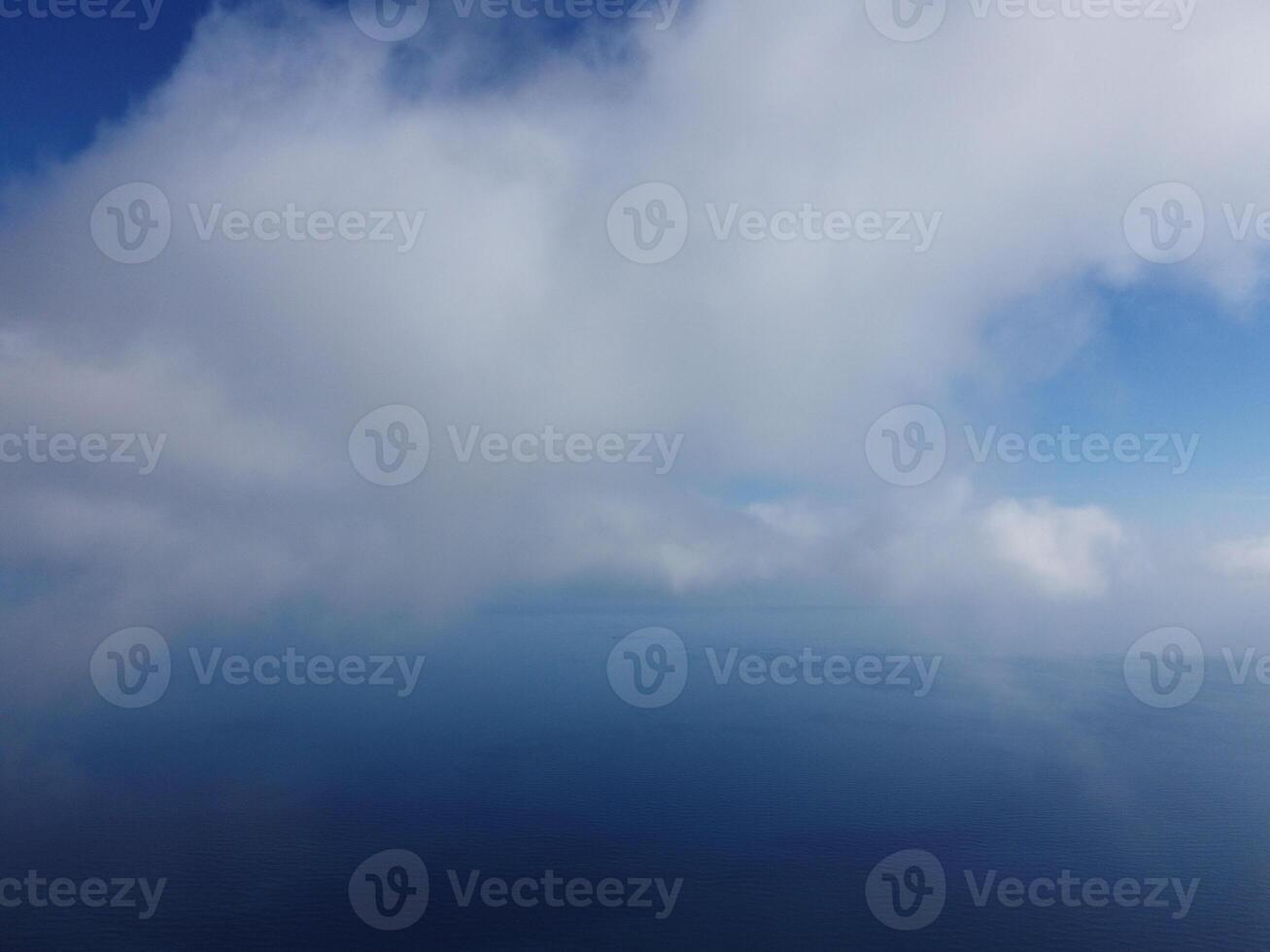 Aerial view. The drone flies over foggy and fluffy clouds. Blue sky sun and sea fog. Abstract aerial nature summer ocean sunset sea and sky background. Vacation, travel and holiday concept photo