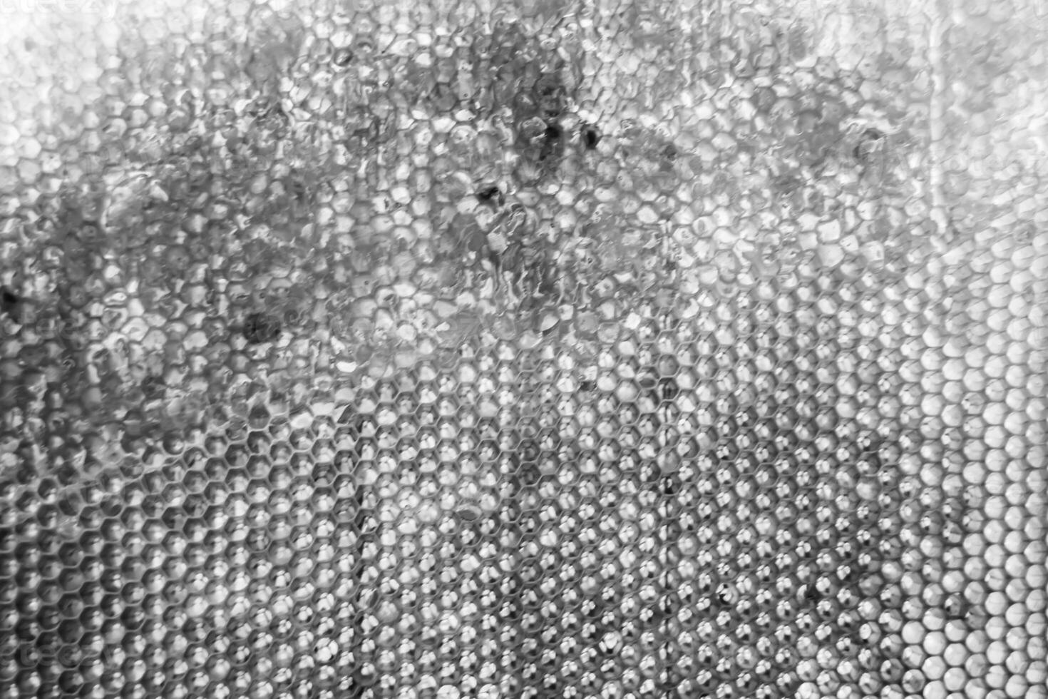 Drop of bee honey drip from hexagonal honeycombs filled with golden nectar photo