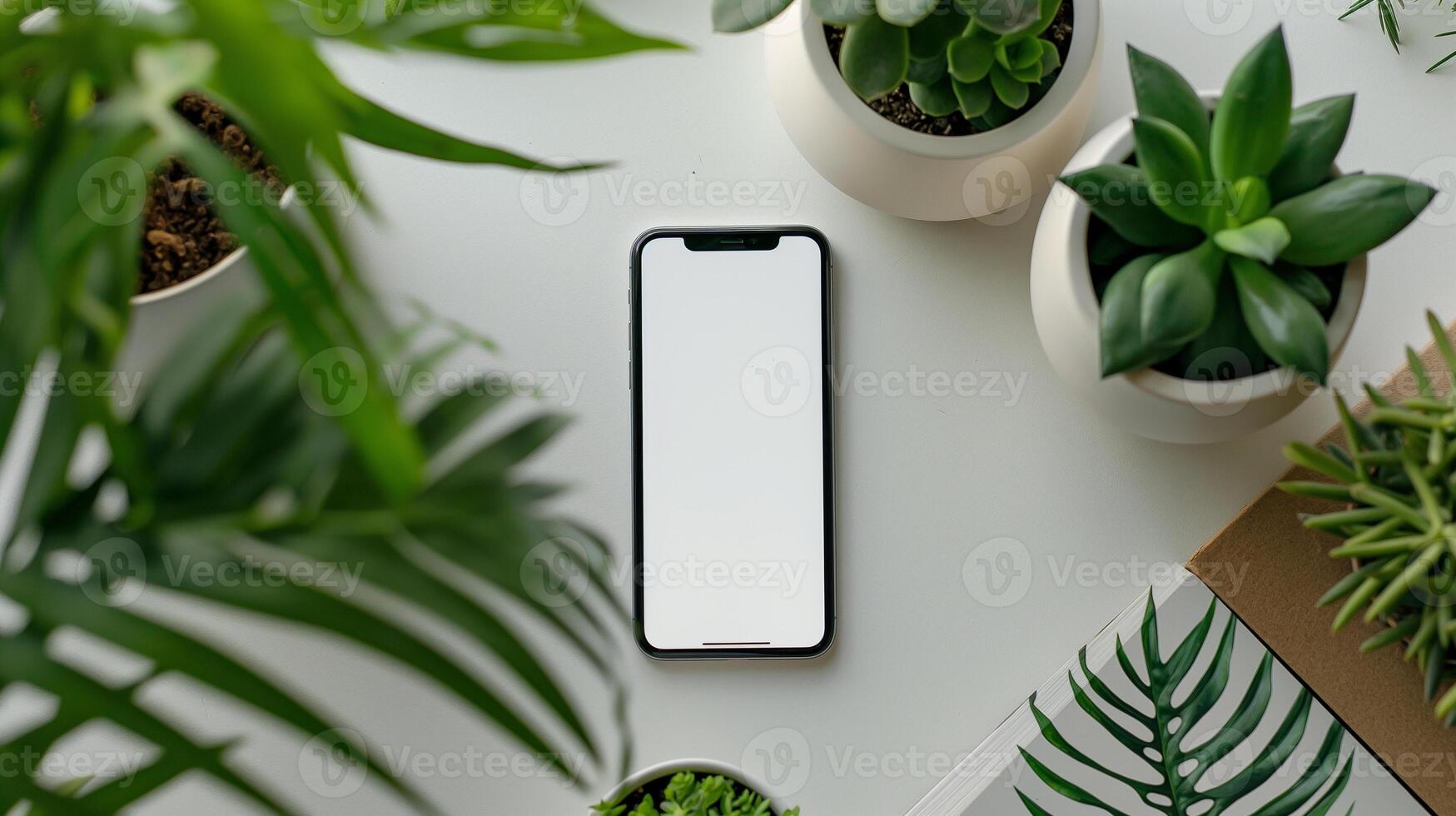 Smartphone with Blank Screen Surrounded by Green Plants on White Table photo