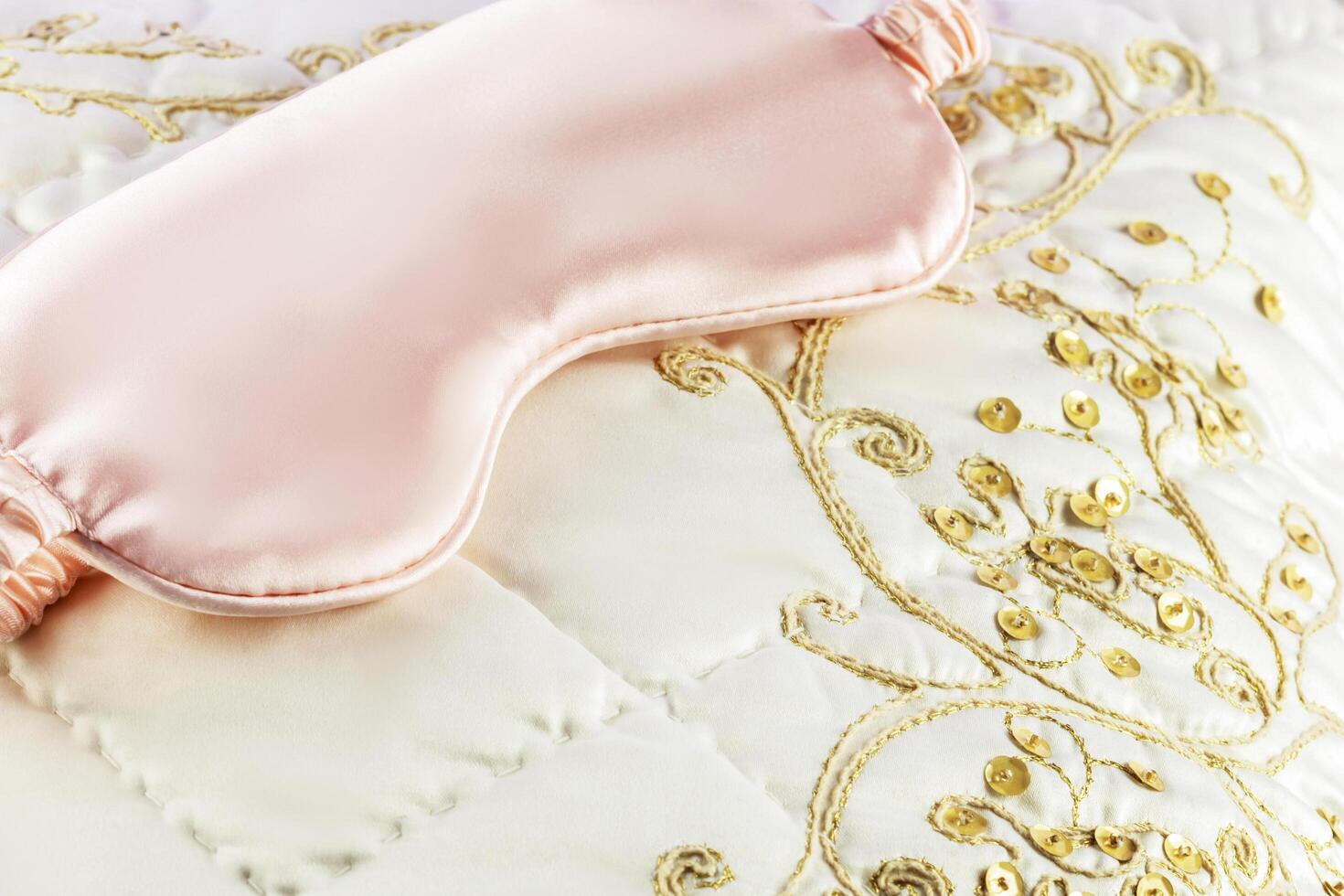 Pink sleep mask on a white silk pillow with embroidery photo