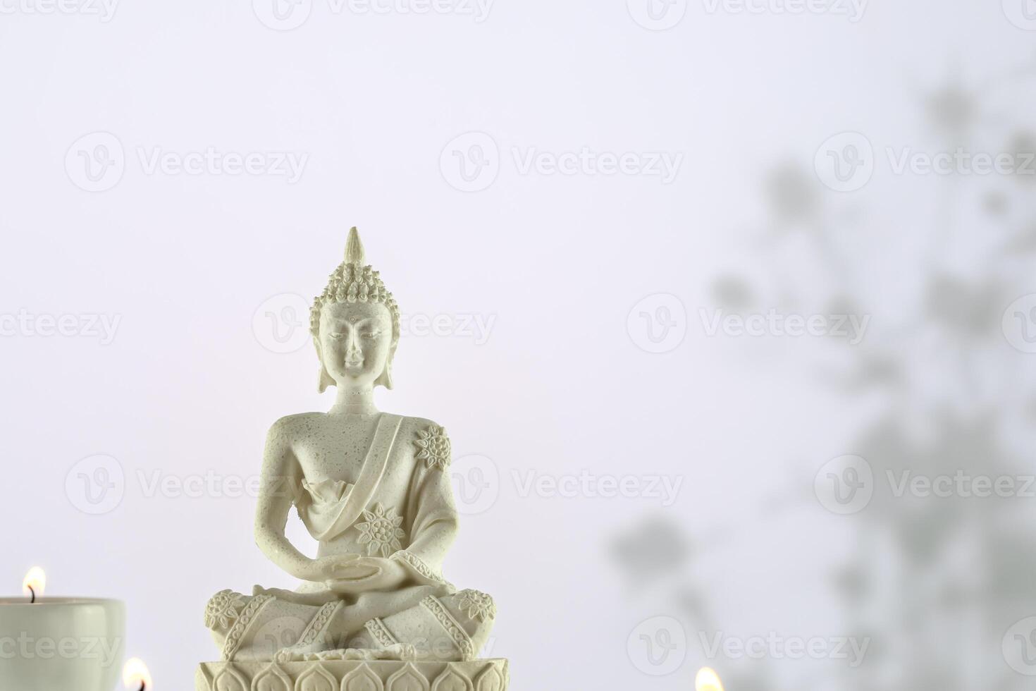 White Buddha statue with candles on a white background with copy space photo