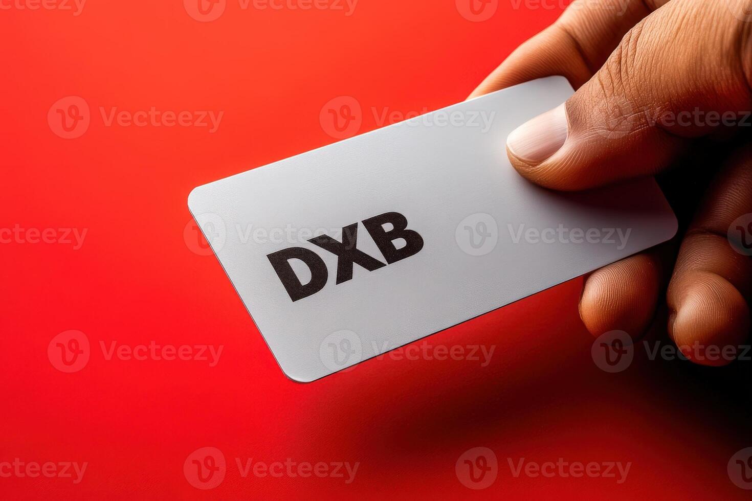 A hand grips a sleek travel card, ready for the next adventure against a striking red backdrop. photo