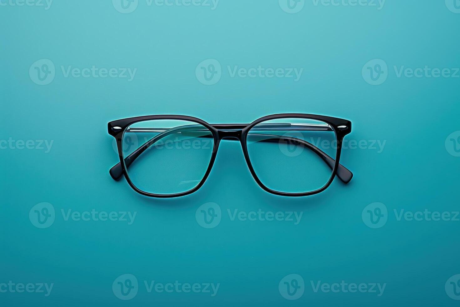 A stylish pair of sleek modern glasses rests elegantly on a bright turquoise surface, showcasing contemporary design and aesthetic appeal. photo