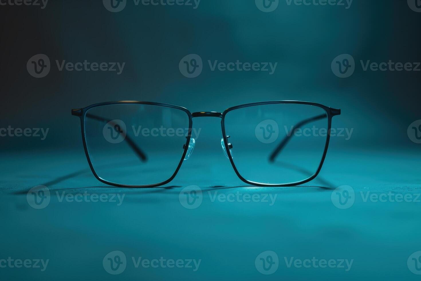 A chic pair of modern glasses rests symmetrically, reflecting light against a calming blue background, creating a stylish focal point. photo