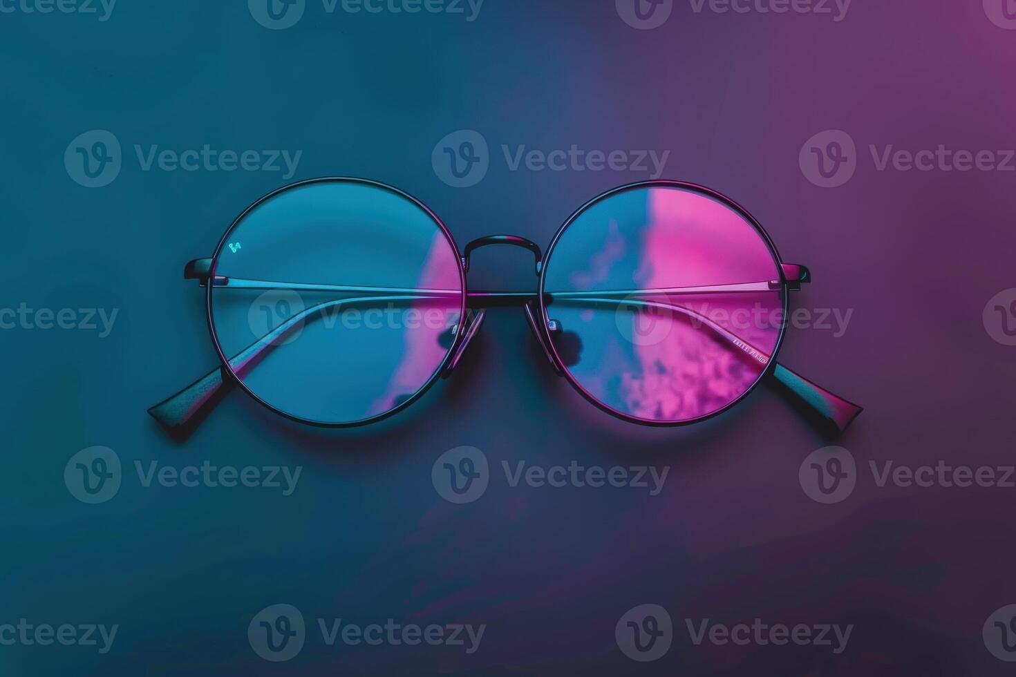 An isolated pair of trendy round glasses showcases playful reflections of pink and blue hues on dark surfaces. photo