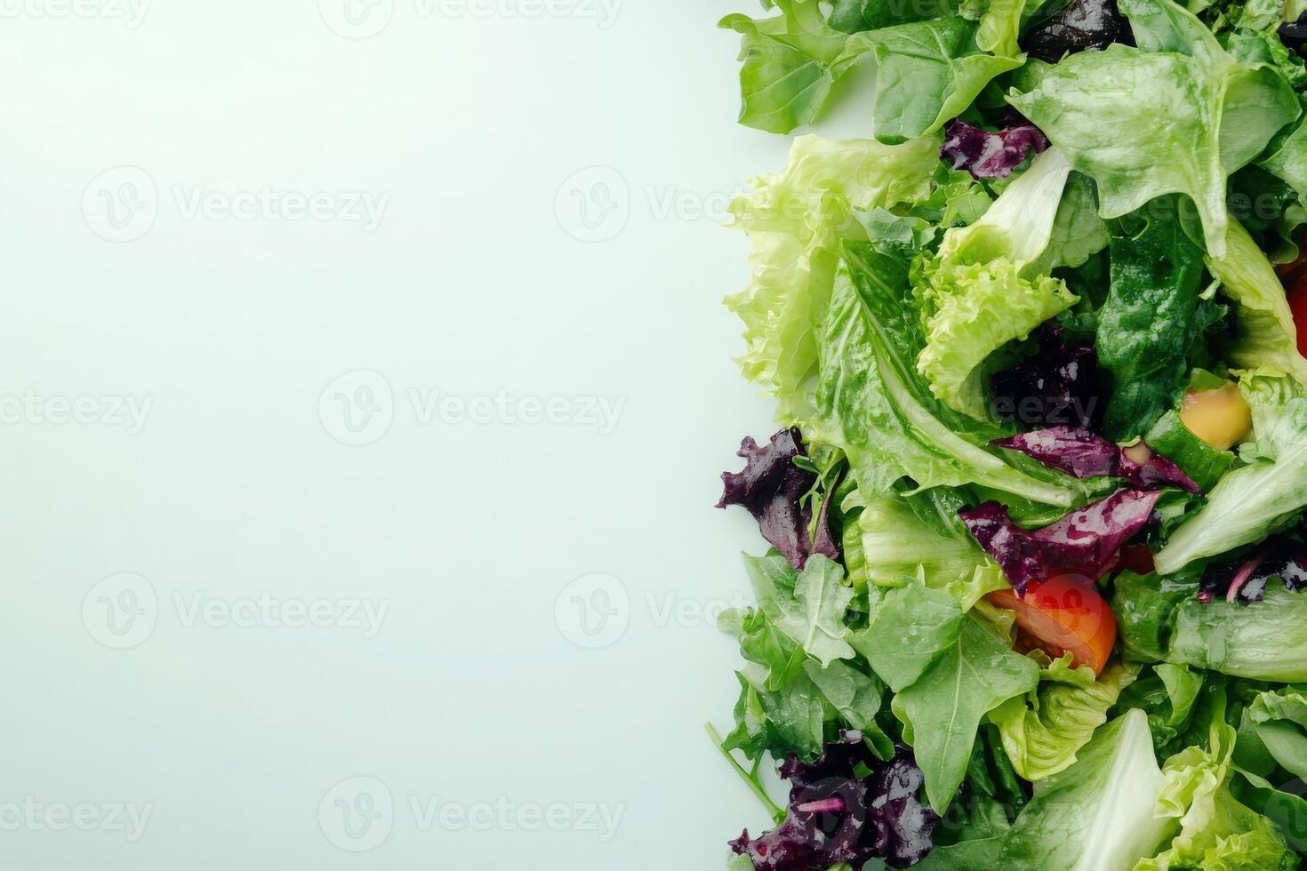 A vibrant assortment of fresh salad ingredients showcases the beauty of greens, with bursts of color from tomatoes and peppers against a clean background. photo