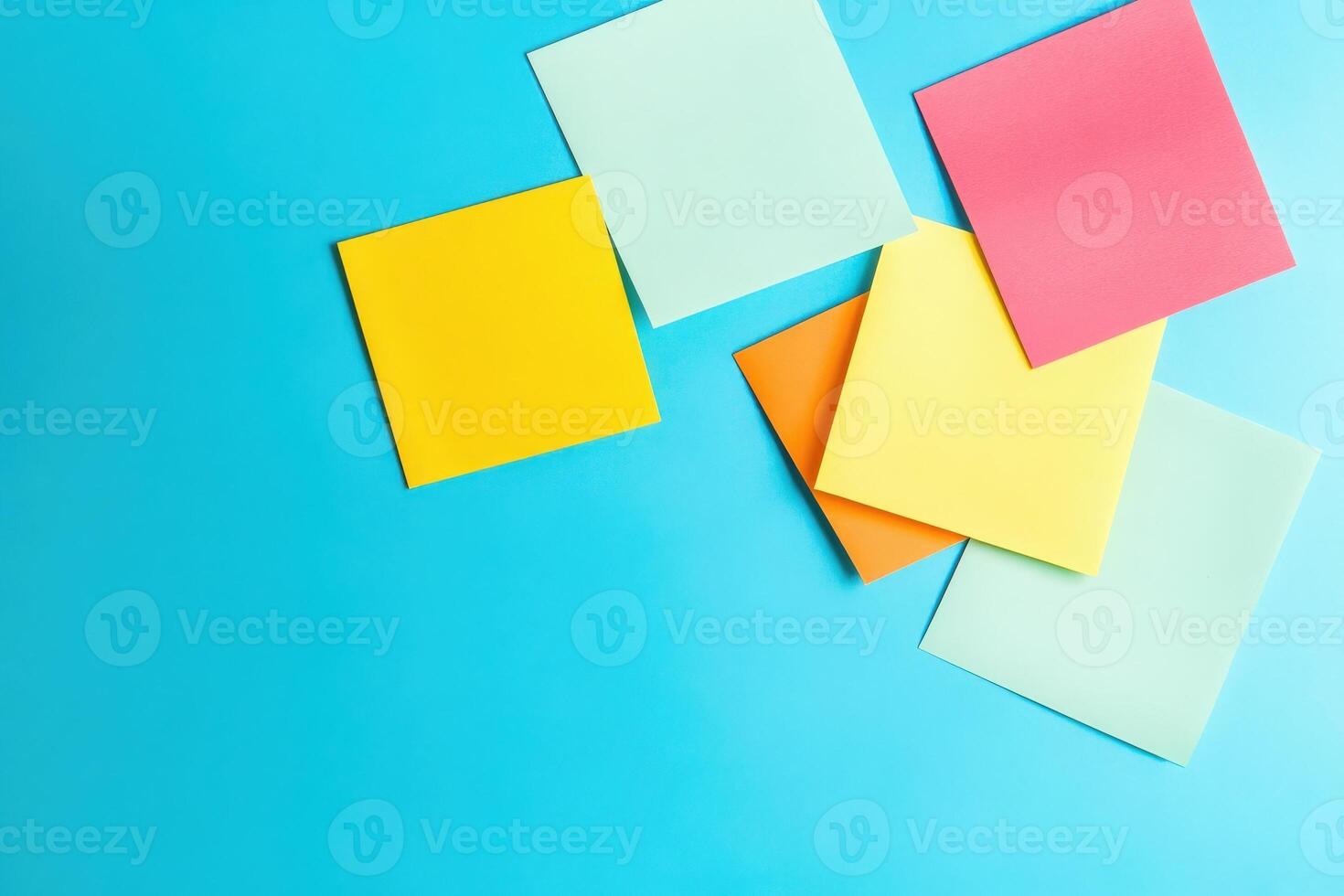 A collection of colorful sticky notes in various shapes and colors contrasts sharply against a bright blue backdrop, inviting creativity and organization. photo