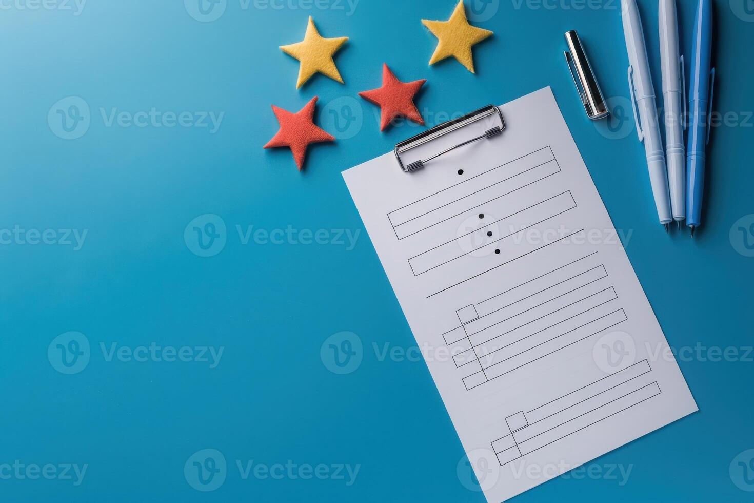 A feedback form lies on a vibrant blue background, accompanied by colorful star shapes and pens, inviting engagement and responses. photo